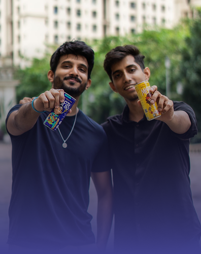 two young men holding beverage cans outdoors in urban setting