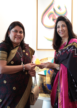 two women exchanging award or gift in formal setting