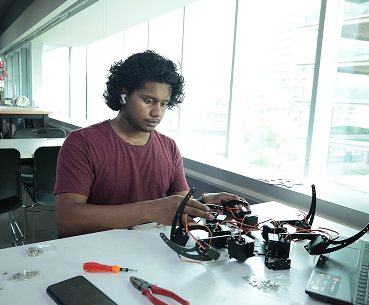 Student assembling a robotics prototype with wires and components